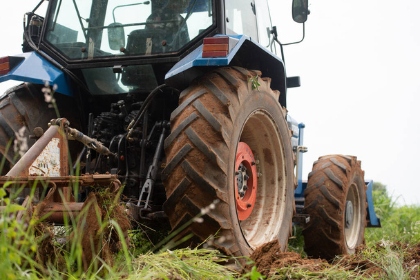 Ein blauer Traktor arbeitet auf einem landwirtschaftlichen Grundstück - Foto, Bild