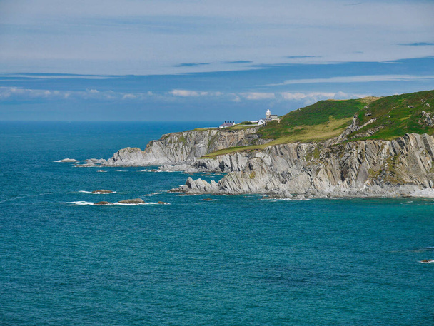 The north Devon coast at Bull Point, showing the Lighthouse and outbuildings. The steeply inclined slate strata of the Morte Slates Formation is visible in the foreground. - Photo, Image