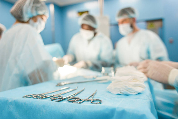 Tools for the operation in the foreground and a team of surgeons in the background performing the operation - Photo, Image