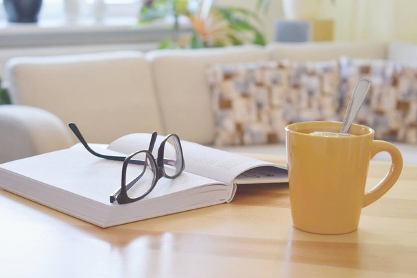Чашка чаю, книга і окуляри на столі, затишний домашній інтер'єр фону
 - Фото, зображення