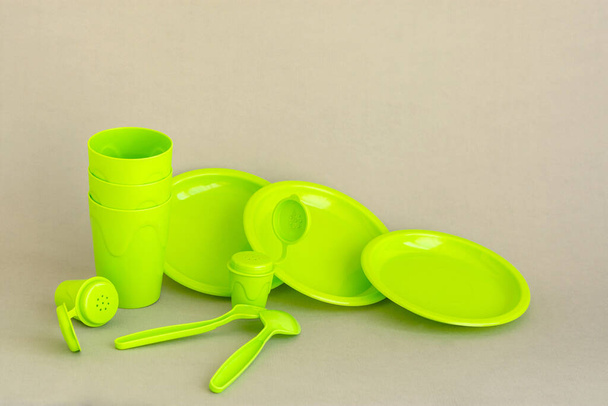 Зеленая пластиковая посуда на сером нейтральном фоне. Набор многоразовых пластиковых блюд для пикника. Загрязнение окружающей среды Еда на вынос. Посуда для отдыха на свежем воздухе
. - Фото, изображение