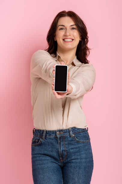 Szelektív fókusz gyönyörű barna nő mutatja okostelefon rózsaszín háttér - Fotó, kép