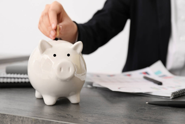 Businesswoman putting money in piggy bank - Foto, immagini