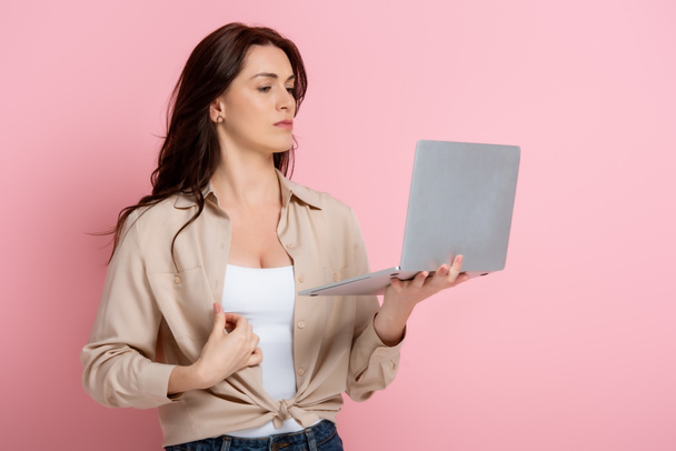 Bella donna bruna che tiene il computer portatile su sfondo rosa - Foto, immagini