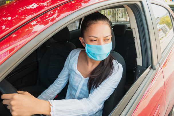 Shot of young woman wearing face mask while driving her car during coronavirus pandemic. - Foto, imagen