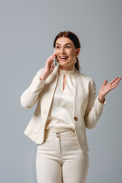 Schöne lächelnde Geschäftsfrau im Smartphone-Gespräch isoliert auf grau  - Foto, Bild