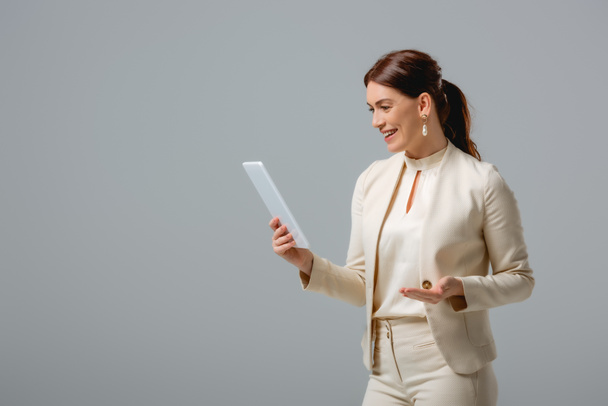 Beautiful businesswoman smiling while holding digital tablet isolated on grey  - Fotografie, Obrázek