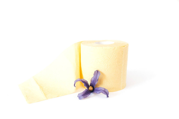 Rollo de papel higiénico amarillo con flor sobre fondo blanco. - Foto, imagen