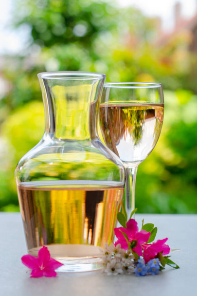 Vin de rose français servi dans le jardin en verre et carafe avec des fleurs de printemps colorées dans la journée ensoleillée - Photo, image