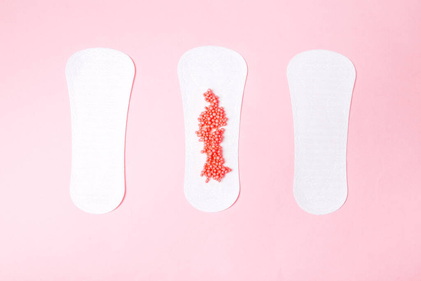 guardanapo sanitário com bolas vermelhas imitando menstruação em um fundo rosa, cuidados de saúde, proteção mensal, amigo confiável. - Foto, Imagem