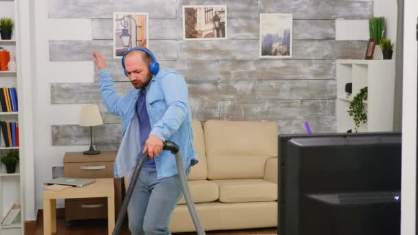 Bold man with blue headphone vacuuming - Záběry, video