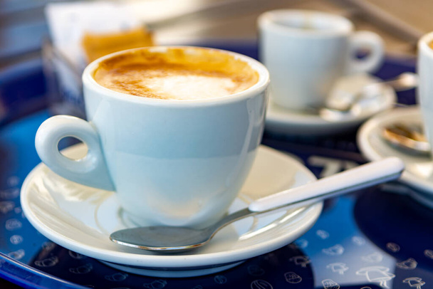 Copo branco com capuccino de café italiano feito de grãos de café torrados frescos e leite quente de perto
 - Foto, Imagem