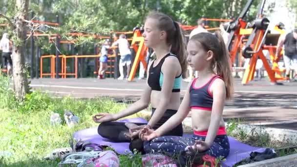 Két lány a sportruházatban kint meditál a sportpályán. Kiváló minőségű FullHD felvételek - Felvétel, videó