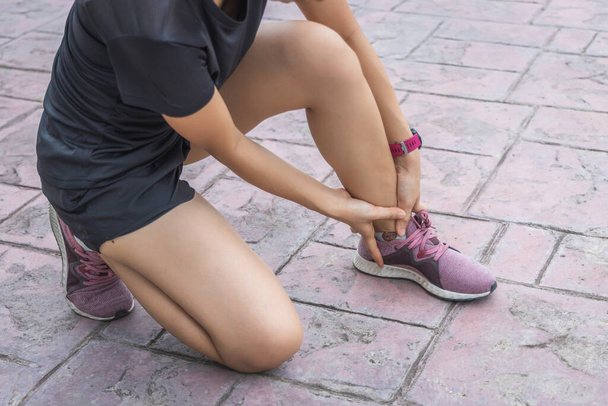The young sport woman holding Ankle in pain suffering muscle injury after running. - Фото, изображение