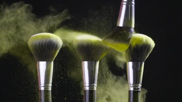 Beauty concept. Cosmetic brush with golden cosmetic powder spreading on black background - Кадры, видео