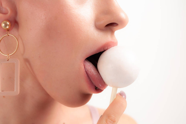 Близько до жіночих губ і цукерок. Дівчина їсть цукерки на паличці. Красиві губи
. - Фото, зображення