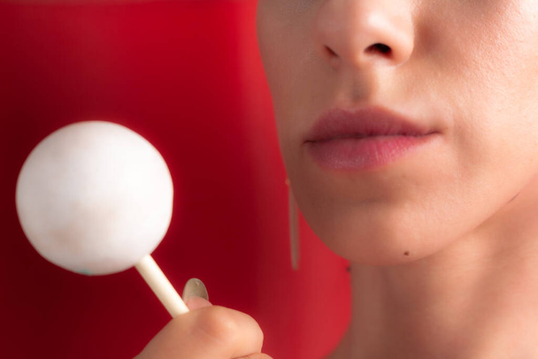 Close up of female lips and candy. Girl eating candy on a stick. Beautiful lips. - Fotó, kép