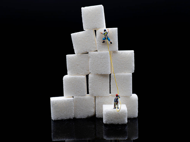 Minikletterer-Team klettert auf Stapel von Zuckerwürfelblöcken - Foto, Bild