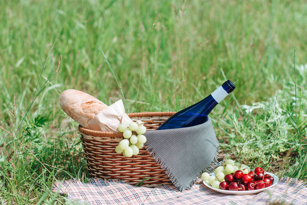 Cesta de picnic con bebidas y comida Sobre tela en el jardín
. - Foto, imagen