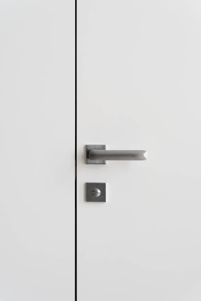 Foto vertical do elemento design de interiores contemporâneo com bloqueio sob alça minimalista na porta fechada e parede do espaço de cópia
 - Foto, Imagem