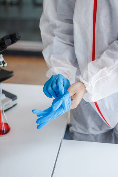 Medische wetenschappers dragen beschermende kleding van het coronavirus en rubberen handschoenen voordat ze het lab ingaan voor onderzoek van het coronavirus. covid-19 en onderzoek naar een vaccin tegen coronavirus covid19 - Foto, afbeelding