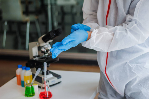 医学者は、コロナウイルスの検査のために研究室に入る前に、コロナウイルス保護服とゴム手袋を着用しています。covid-19とコロナウイルス対策ワクチンの研究 - 写真・画像