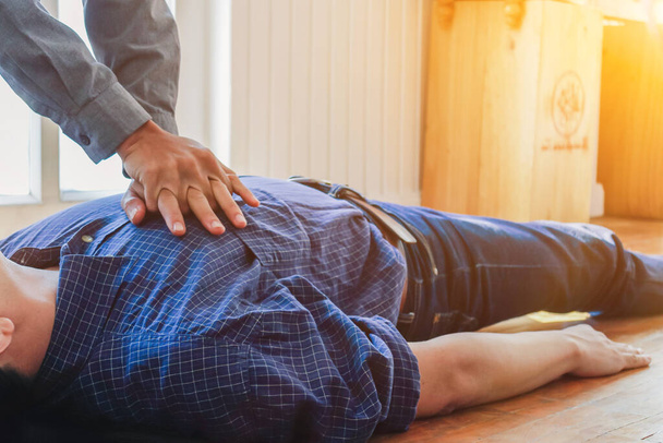 Der junge Mann hilft seinem bewusstlosen Freund und hört auf, auf dem Boden mit CPR zu atmen, da er zuvor trainiert hatte, das Bewusstlose zu retten und aufgehört zu atmen. - Foto, Bild