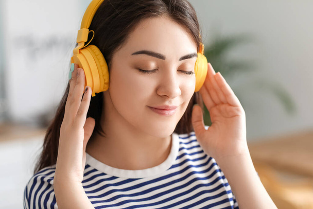 Kaunis nuori nainen kuuntelee musiikkia keittiössä
 - Valokuva, kuva