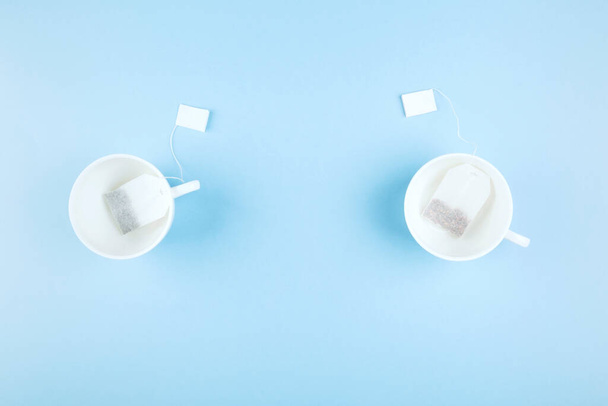 Cups of tea and tea bags on blue background. Top view, copy space. Food background - Foto, imagen