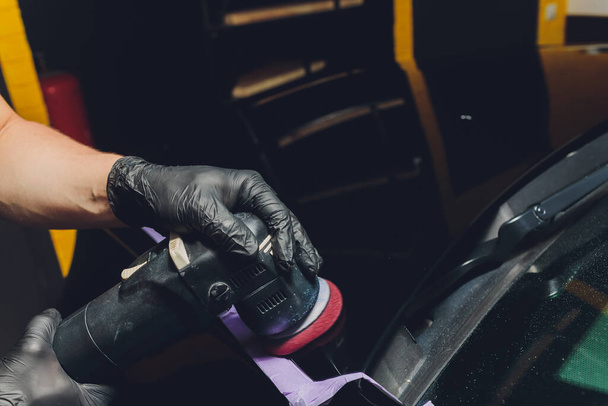 Car detailing - Hands with orbital polisher in auto repair shop. Selective focus. - Foto, Imagem