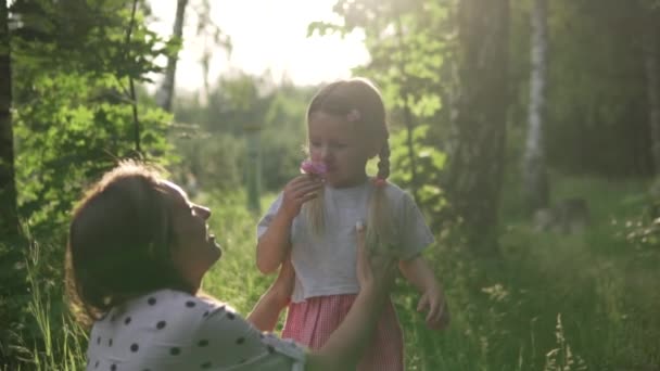 Ευγενική μαμά και κόρη σε μια βόλτα μέσα από το πάρκο το ηλιοβασίλεμα - Πλάνα, βίντεο