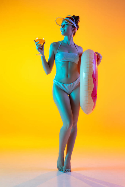 Fashion portrait of seductive girl in stylish swimwear posing on a bright yellow background. Summertime, beach season - Foto, Bild