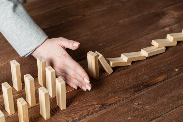 Businesswoman protecting dominoes from falling - Foto, Imagem