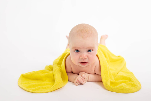 Beyaz bir arka planda banyo yaptıktan sonra havluyla küçük bir kız kameraya bakar, bebek 3-6 ay, mesaj için zaman ayırır. - Fotoğraf, Görsel