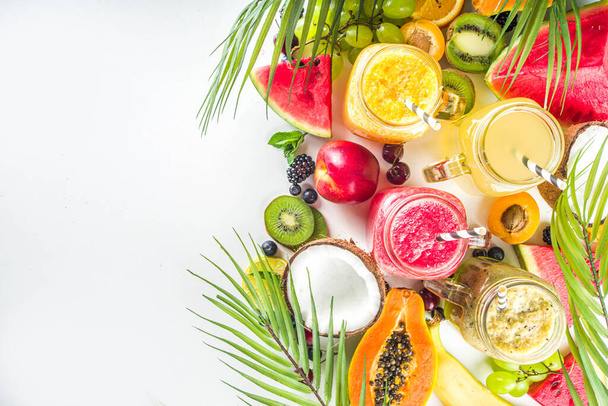 Valikoima erilaisia hedelmäsmoothieita ja mehuja trooppisilla tuoreilla hedelmillä ja marjoilla. Puhdas syöminen, terveelliset elämäntavat, ruokavalio ja vitamiinijuomat käsite. Top view flatlay valkoinen pöytä tausta  - Valokuva, kuva
