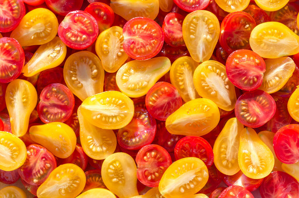 Moitiés fraîches de tomates cerises mexicaines. Tomates cerises jaunes et rouges tranchées.Fond de nombreuses tomates cerises colorées. Tomates cerises vue du dessus. - Photo, image