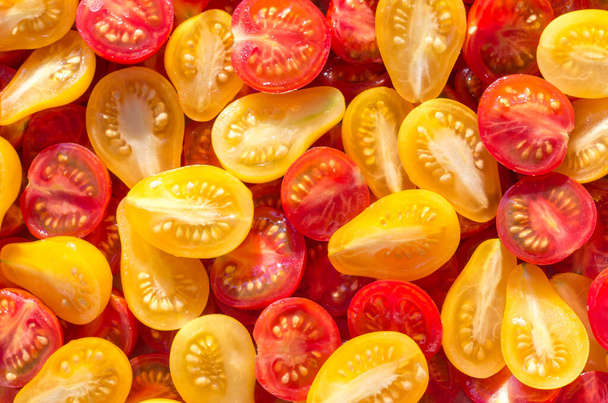 Fresh halves of Brazilian cherry tomatoes. Background of many colorful cherry tomatoes. Cherry tomatoes top view. Sliced yellow and red cherry tomatoes - Photo, Image