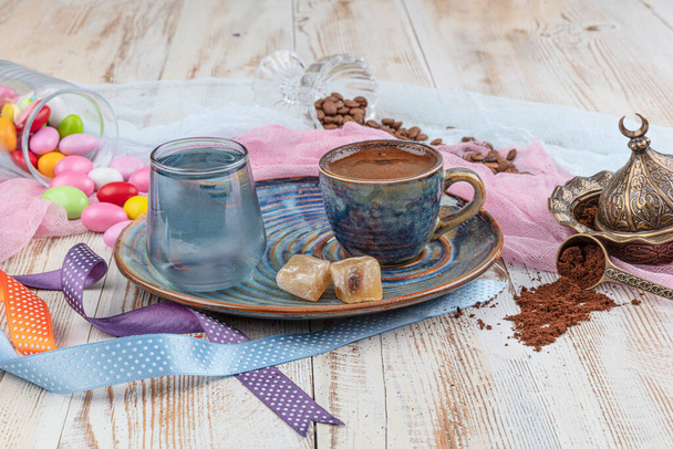 Traditionele Turkse koffie in porseleinen bekerset, een glas water en Turks genot, kleurrijke amandelsnoepjes op het oppervlak met koffiebonen. Een feest (feest) klassieker, Ramadan feest catering presentatie. - Foto, afbeelding