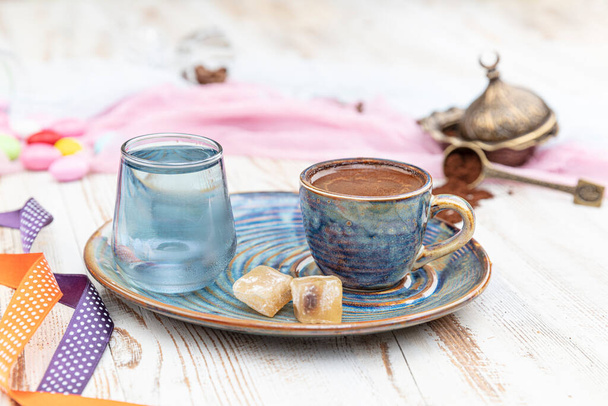 Traditionele Turkse koffie in porseleinen bekerset, een glas water en Turks genot, kleurrijke amandelsnoepjes op het oppervlak met koffiebonen. Een feest (feest) klassieker, Ramadan feest catering presentatie. - Foto, afbeelding