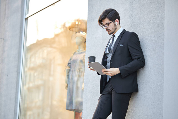 Young Businessman using a tablet pc outside wearing a classic suit - Fotó, kép