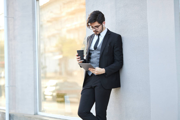 Young Businessman using a tablet pc outside wearing a classic suit - 写真・画像