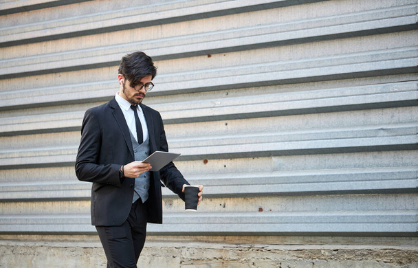 Young Businessman using a tablet pc outside wearing a classic suit - Foto, imagen