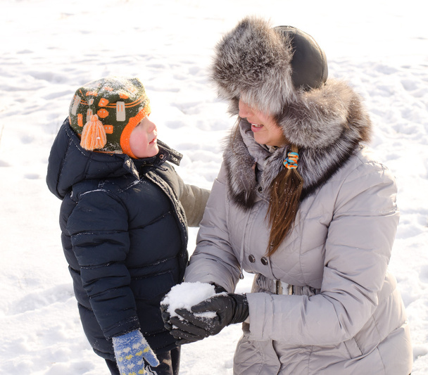 雪の中で彼の母親と一緒に遊んでかわいい男の子 - 写真・画像