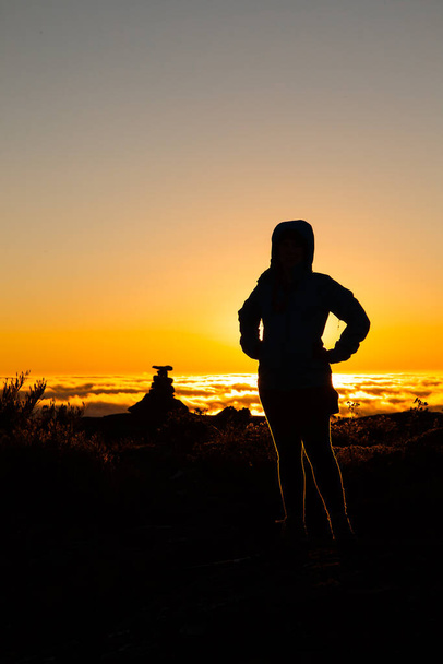 Силуетна дівчина підсвічується на вершині гори на заході сонця
 - Фото, зображення