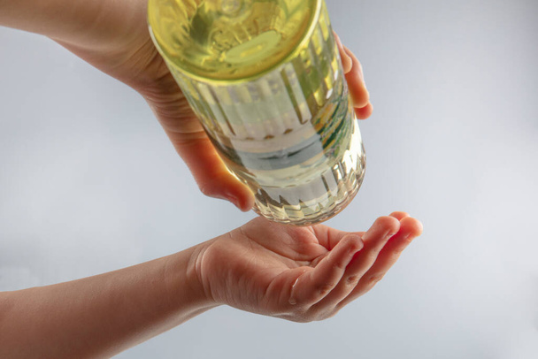 Klein meisje desinfecteert handen met parfum. Turkse citroenparfum met 80 graden alcohol voor desinfectie en het doden van de virussen op je handen. - Foto, afbeelding