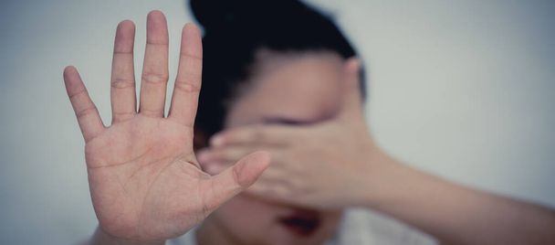 Wizerunek kobiety podnoszącej rękę, aby zakazać lub zakryć twarz, aby pokazać opór i chce zatrzymać przemoc Concept Violence wobec kobiet w białym tle. - Zdjęcie, obraz