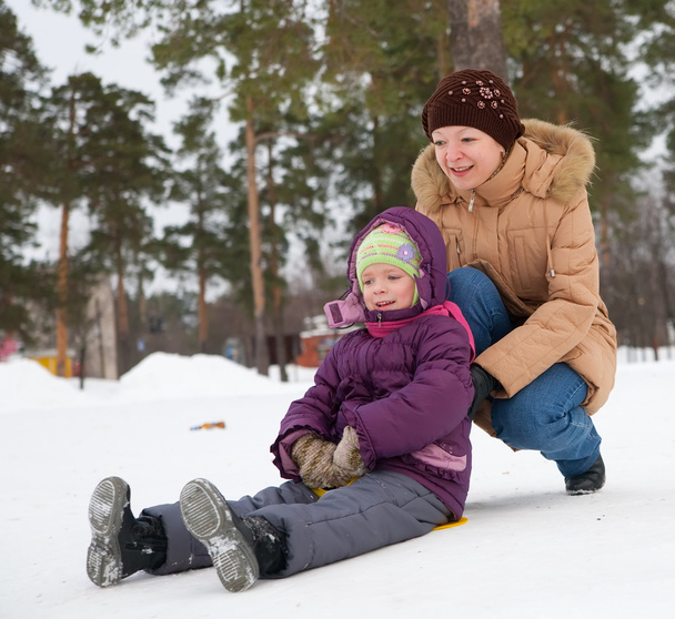 Enfant glissant dans la neige avec sa mère
 - Photo, image