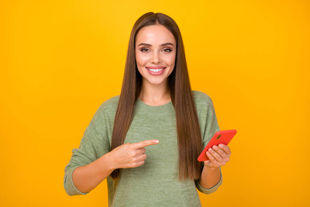 Portrait of positive cheerful girl promotion blogger use cellphone point index finger present social network adverts wear jumper isolated over bright shine color background - Photo, Image