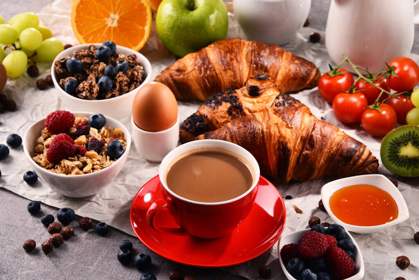 Frühstück mit Kaffee, Orangensaft, Croissants, Ei, Müsli und Obst. Ausgewogene Ernährung. - Foto, Bild