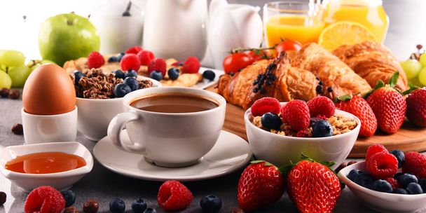 A reggelit kávé, narancslé, croissant, tojás, gabonafélék és gyümölcsök kísérik. Kiegyensúlyozott étrend. - Fotó, kép